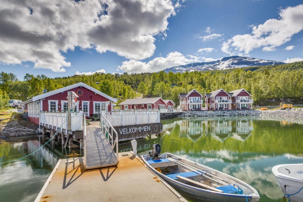 a dock with a boat on the water with houses at Garsnes Brygge in Sjøvegan