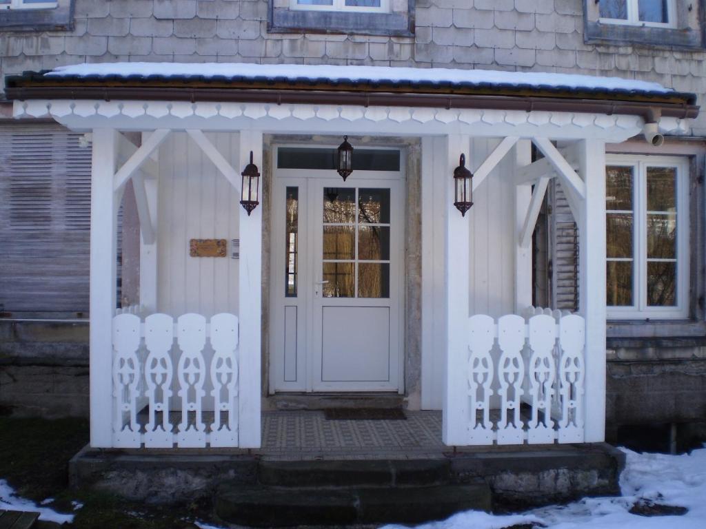 a white front door of a house with snow on it at Chambres d'Hôtes le Clos des Lesses in Fresse-sur-Moselle