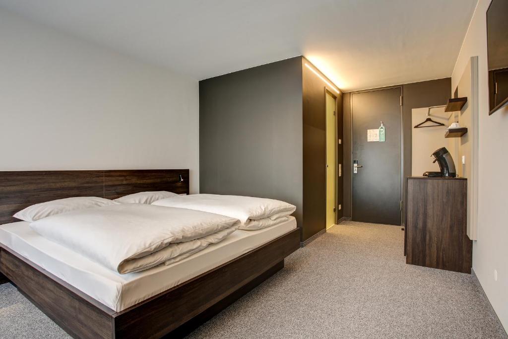 a bedroom with a large bed with a wooden headboard at Centro Parkhotel Stuttgart in Ostfildern