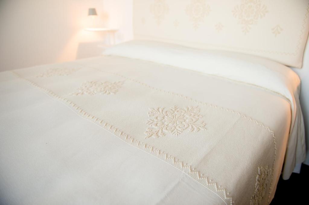 a white bed with a white blanket on it at Faro Capo Spartivento in Chia