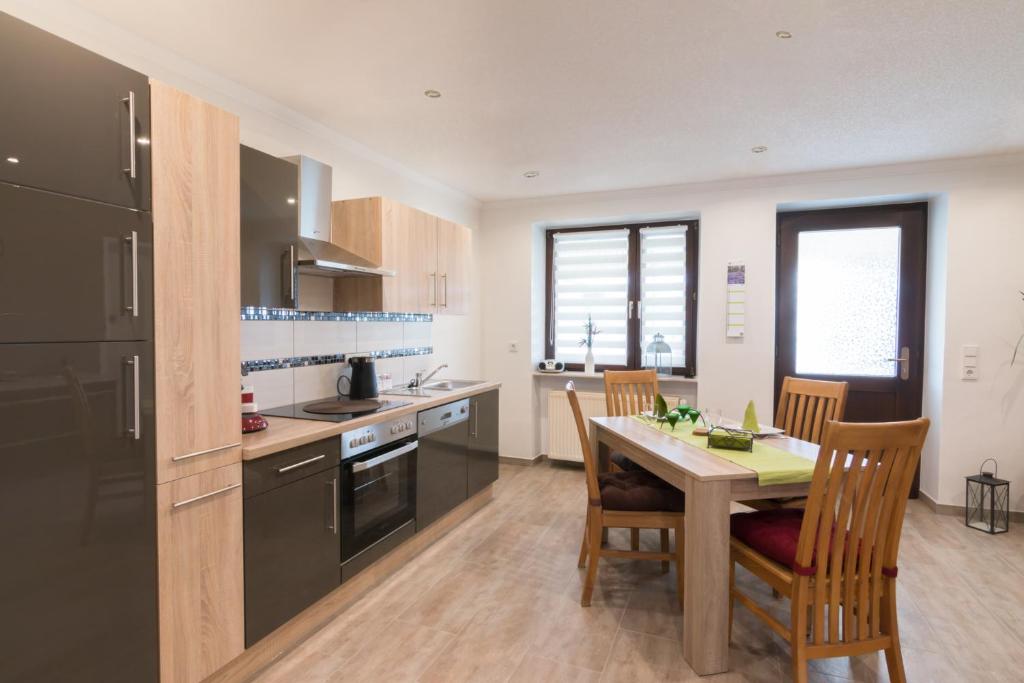 una cocina con mesa de madera y sillas y una cocina con electrodomésticos negros. en Ferienwohnung Ulrike, en Blieskastel