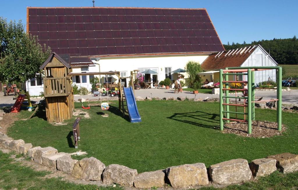 un parco giochi con un edificio con tetto solare di Ferienbauernhof Herrmann a Herrieden