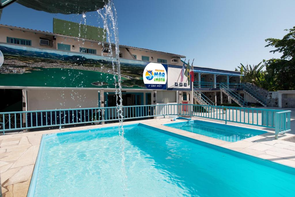 a pool with a water fountain in front of a hotel at Pousada Mar E Mata in Guarapari