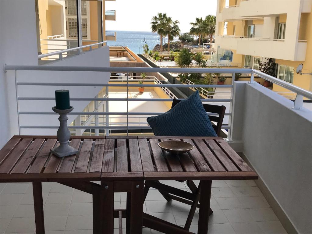 a wooden table and chair on a balcony with a view of the ocean at Apartamento T&T Ocean - Vista Mar in Portimão