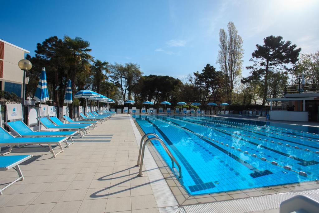 ein großer Pool mit blauen Stühlen und Sonnenschirmen in der Unterkunft Hotel Beau Soleil in Cesenatico
