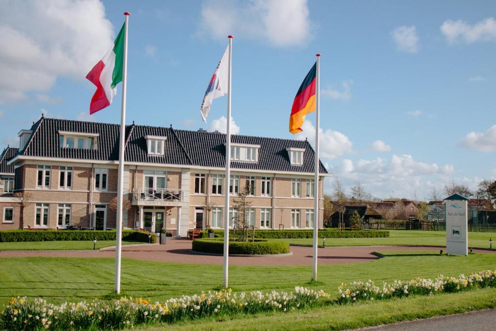 un bâtiment avec trois drapeaux devant lui dans l'établissement Residence Aan de Kust, à Noordwijk aan Zee