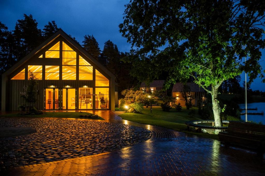 un grand bâtiment en verre avec un banc devant lui dans l'établissement Barono Vila, à Butėnai