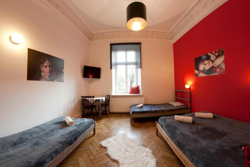 Habitación con 2 camas y pared roja. en Pokoje Bagatela Stare Miasto, en Cracovia