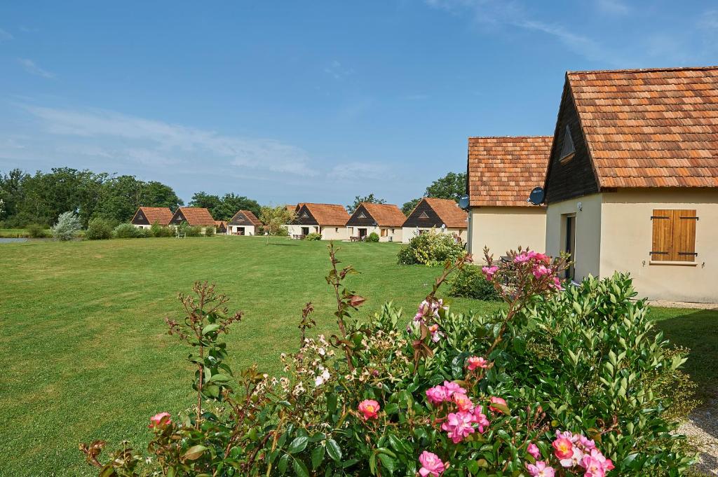 a row of houses in a field with flowers at Le Lac Bleu in Lacapelle-Marival