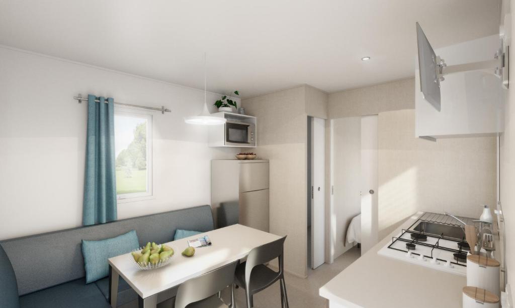 um pequeno apartamento com uma cozinha, uma mesa e um quarto em Campeggio Ai Colli Fioriti em Castiglione dʼIntelvi