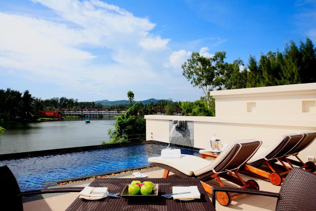 a patio with chairs and a swimming pool at Dusit Thani Laguna Phuket in Bang Tao Beach
