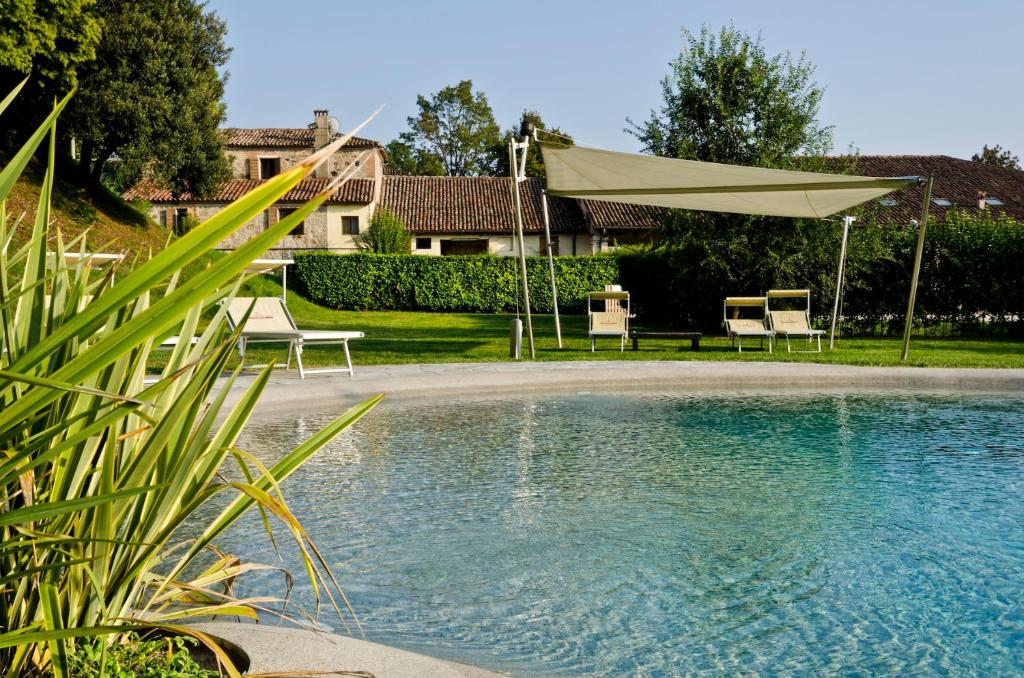 a swimming pool with a tan umbrella and chairs at Agriturismo La Montecchia in Selvazzano Dentro