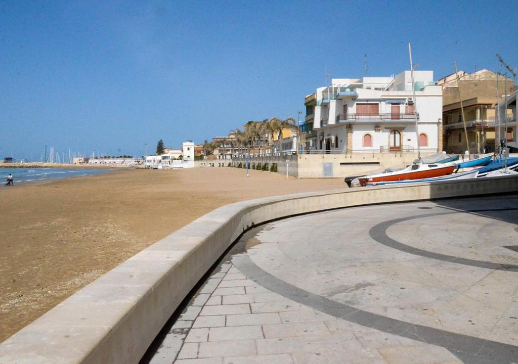 einen Strand mit Booten auf dem Sand und Gebäuden in der Unterkunft Villetta Via Fregene in Marina di Ragusa