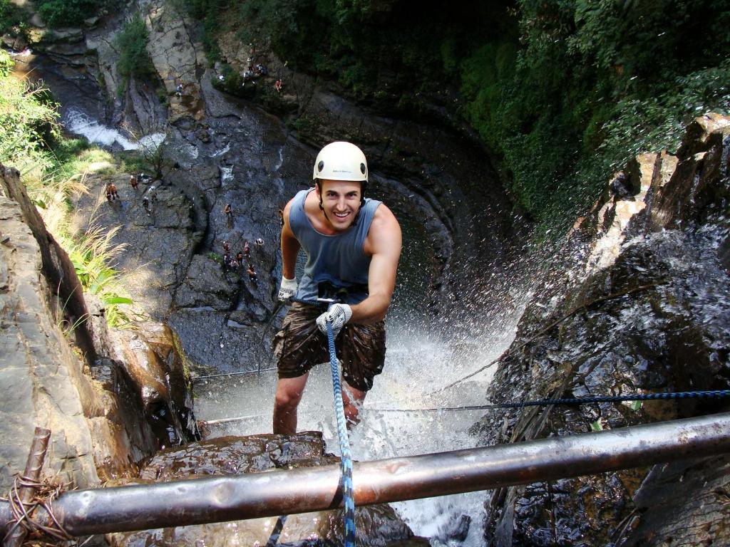 a man standing on a rope bridge in a waterfall at Macondo Hostel in San Gil