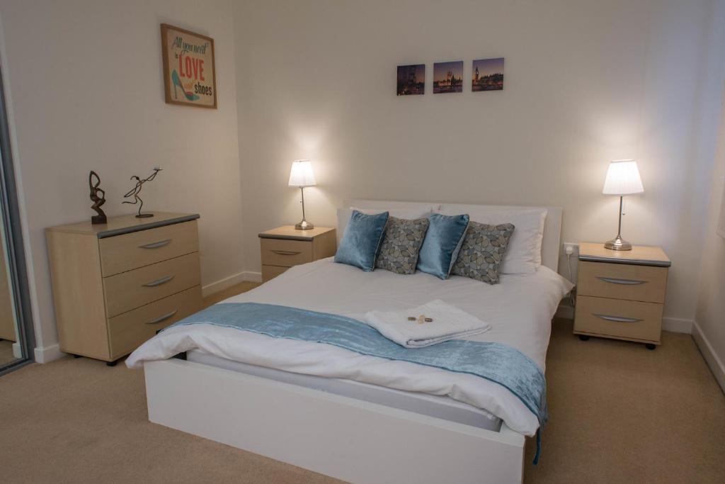 ロンドンにあるRoyal Limehouse Apartmentのベッドルーム1室(白いベッド1台、ナイトスタンド2台付)