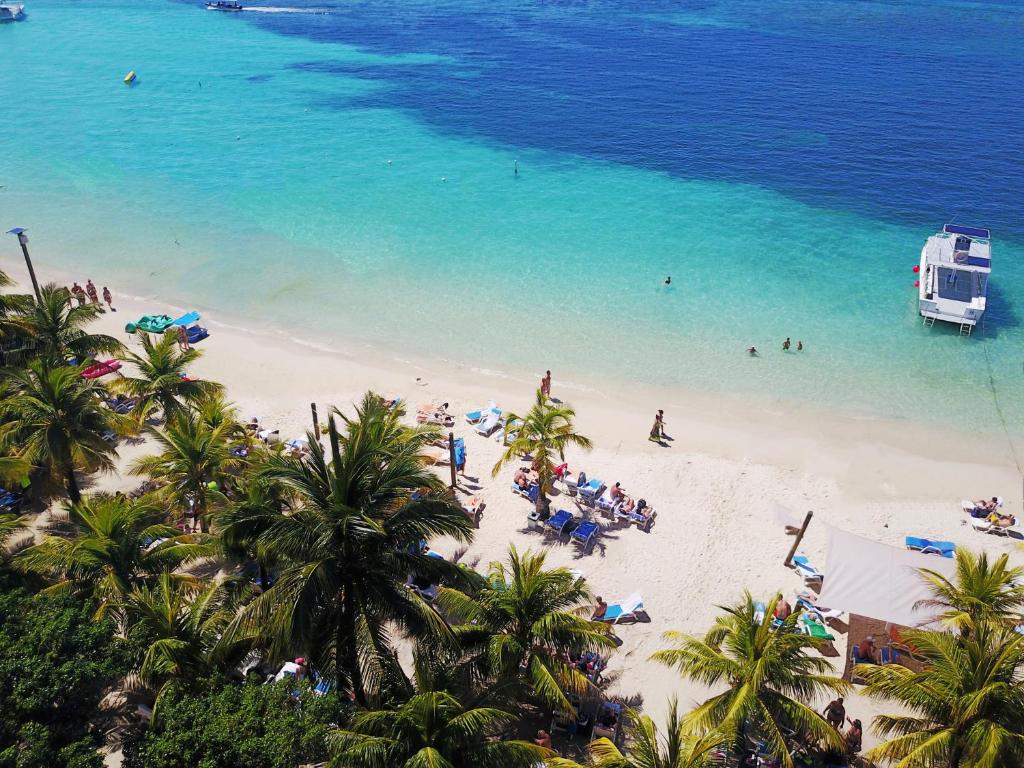 eine Gruppe von Menschen am Strand mit dem Meer in der Unterkunft Hotel Henry Morgan All Inclusive in West Bay