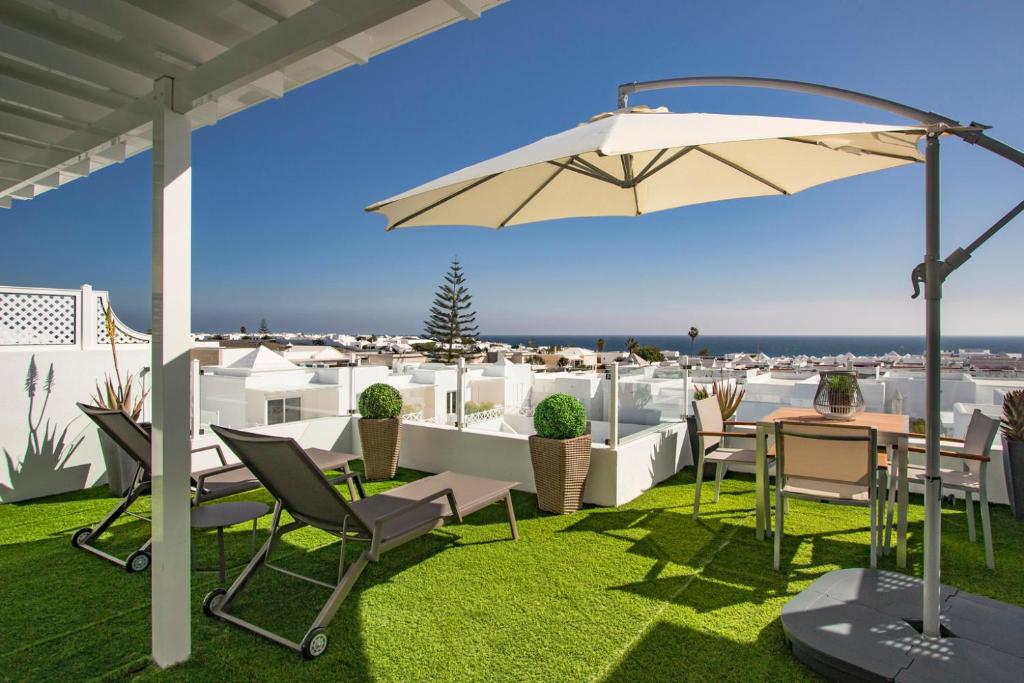 een terras met een tafel, stoelen en een parasol bij Flower Beach Suite 23 in Playa Honda