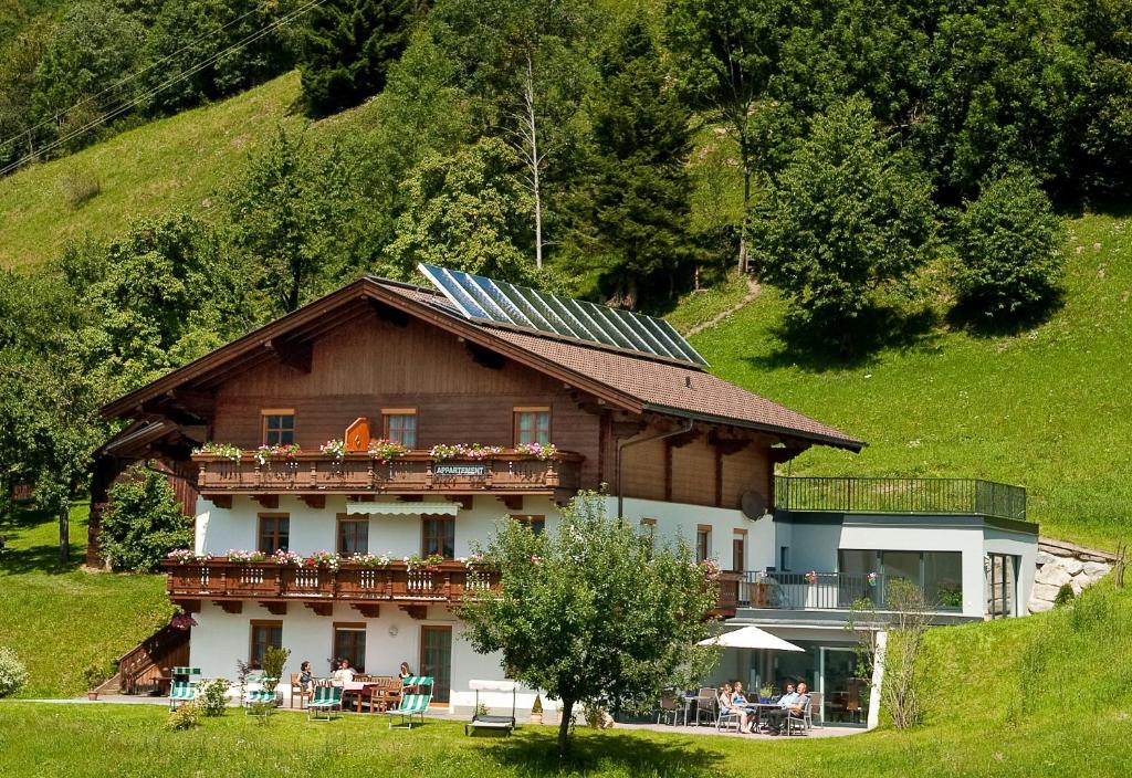 a house with a balcony with people sitting on it at Appartements Hartlbauer in Dorfgastein
