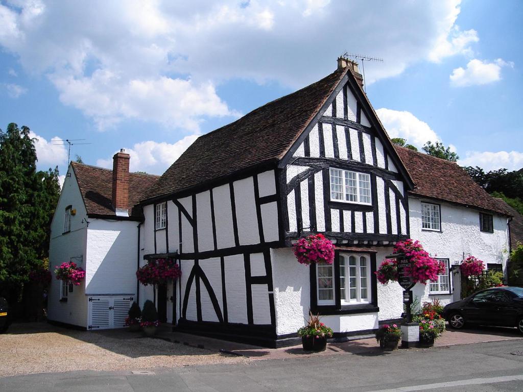 a black and white building with pink flowers on it at Park Cottage in Warwick