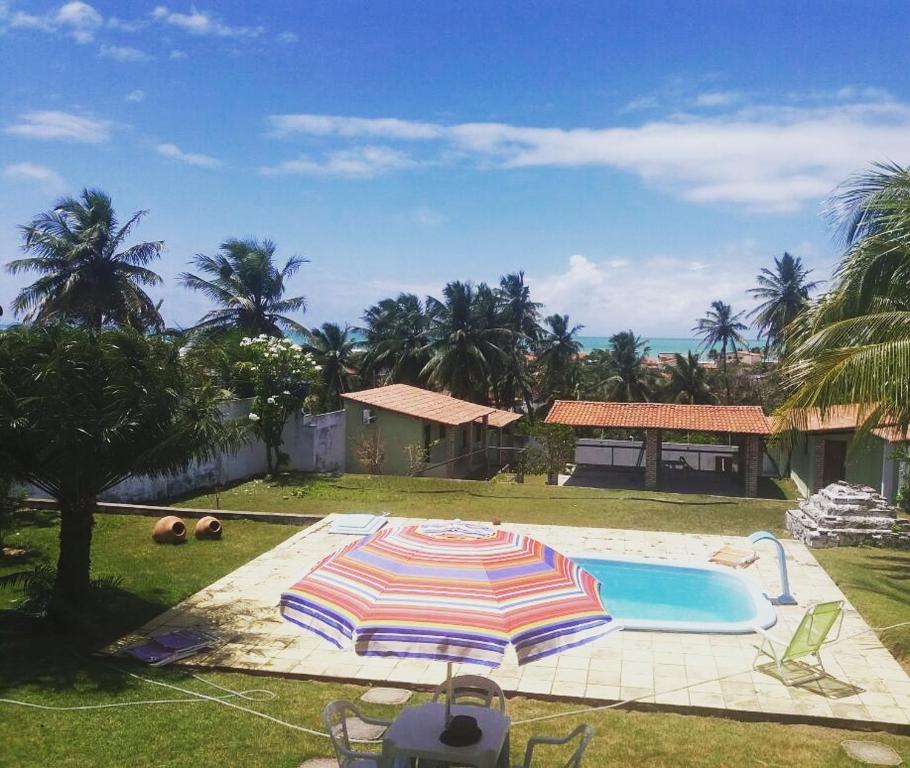 a swimming pool with an umbrella in a yard at Pousada Cruzeiro dos Anjos in Tabatinga