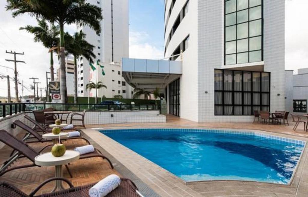 una piscina con tumbonas y un edificio en Quality Suites Natal, en Natal
