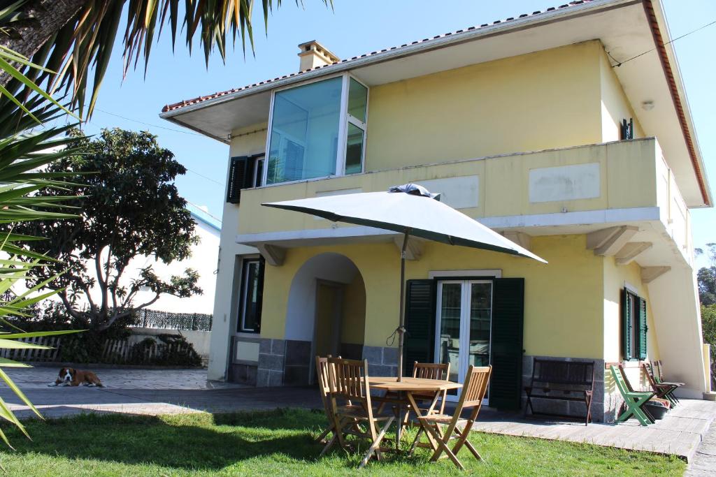 une table avec un parasol devant une maison dans l'établissement Casa de alojamento local (T2) Queluz de Baixo, à Oeiras