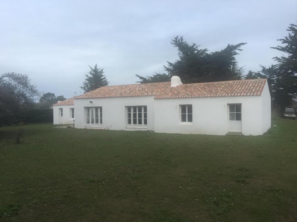 una casa blanca en un campo con un patio en Les Genets, en Ker borny