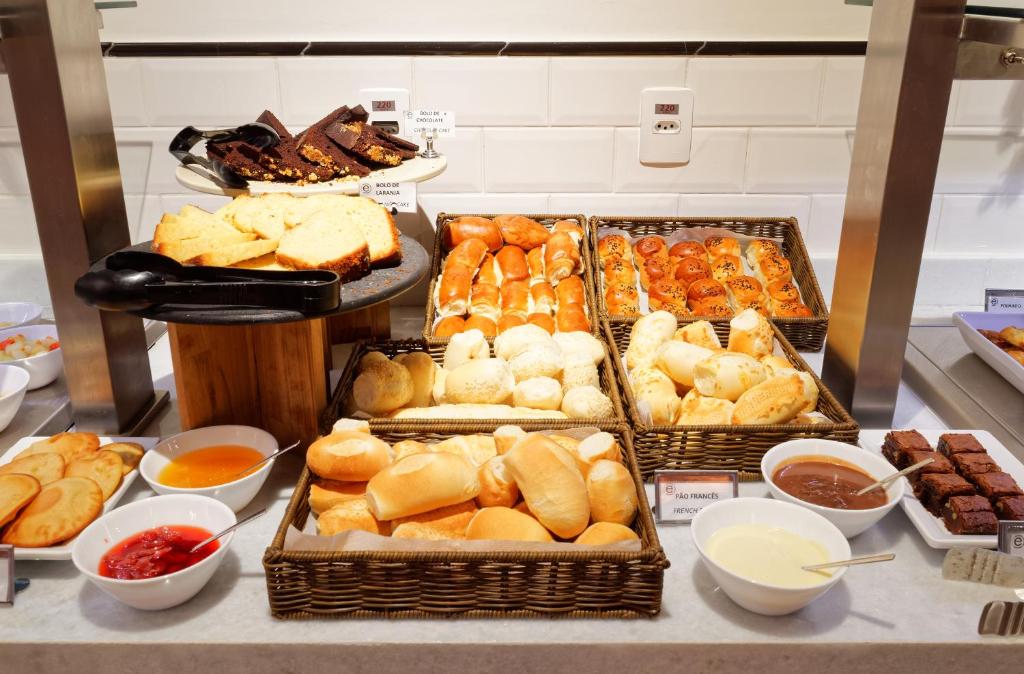 a buffet filled with different types of bread and pastries at Ramada Encore Sao Paulo Tiradentes Centro in Sao Paulo