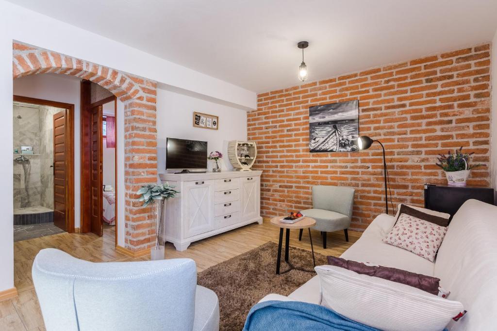 a living room with a white couch and a brick wall at Apartments Rensi in Zadar