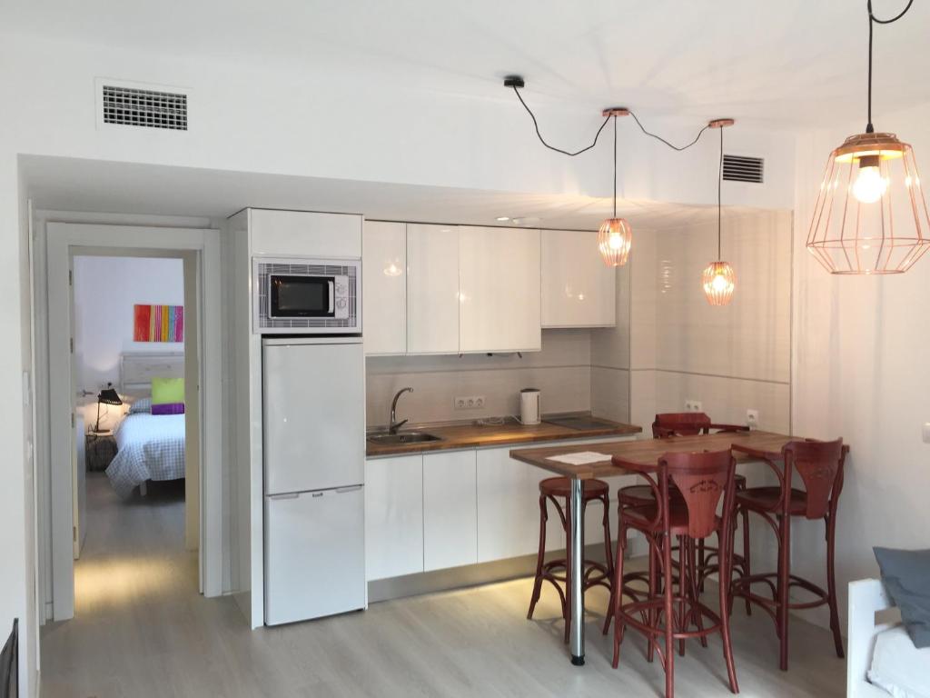 グラナダにあるRealejo Center Apartments 2 bedroomの白いキャビネット、テーブルと椅子付きのキッチンが備わります。