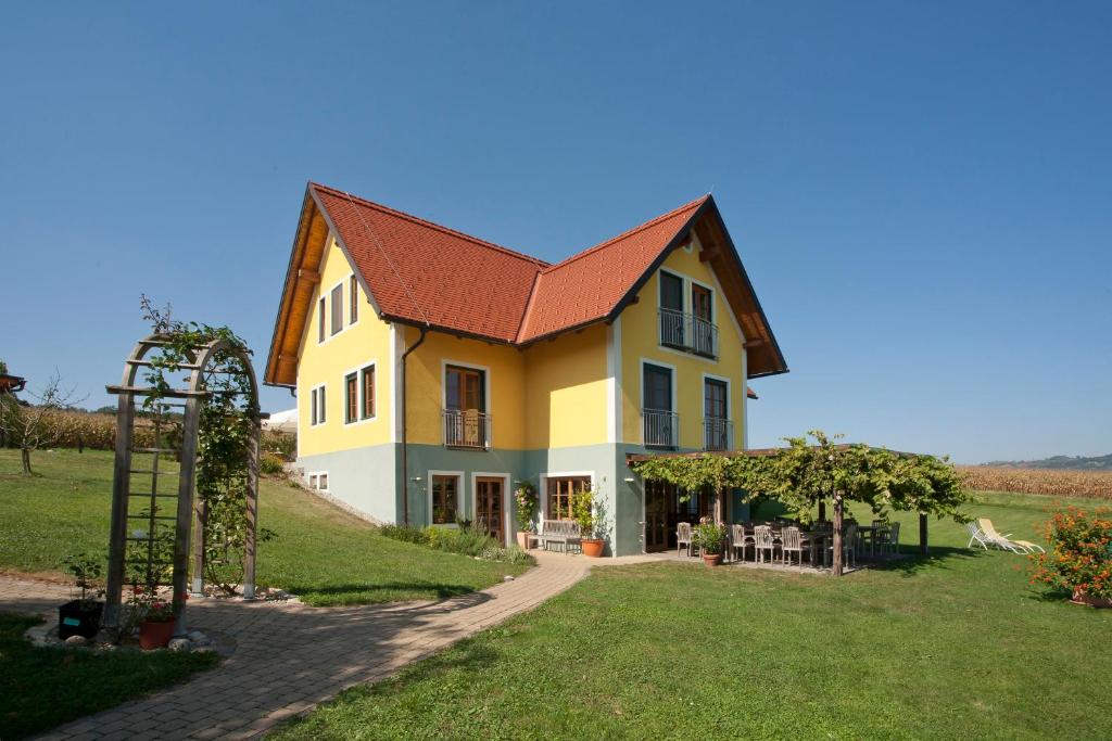 une grande maison jaune avec un toit rouge dans l'établissement Weingut Winzerhof Gästezimmer Grebenz, à Großklein