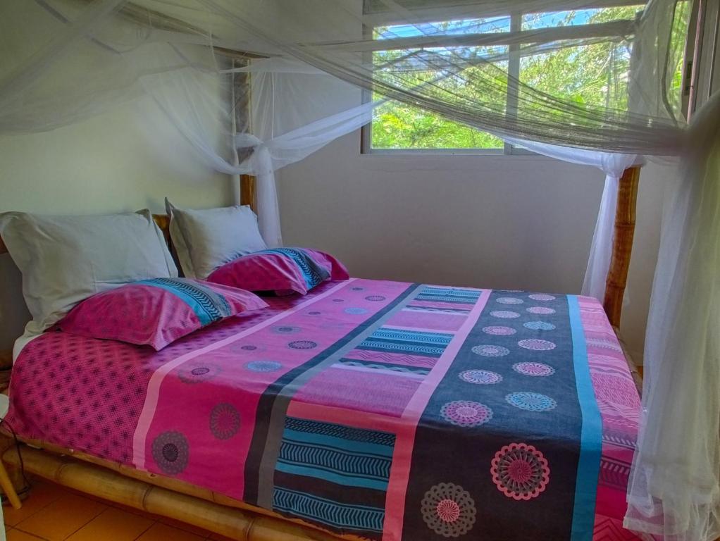 a bedroom with a bed with a colorful comforter and a window at Le Parc aux Orchidées in Pointe-Noire