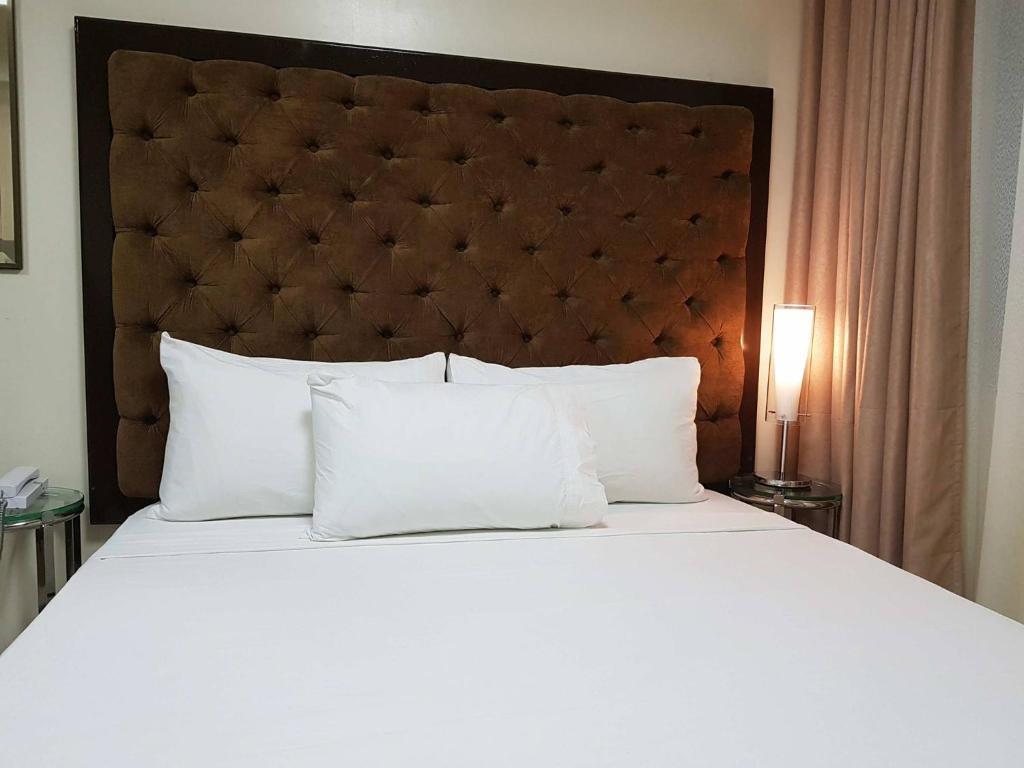 een slaapkamer met een groot bed met witte kussens bij Studio Unit at The Breeze Residences in Manilla