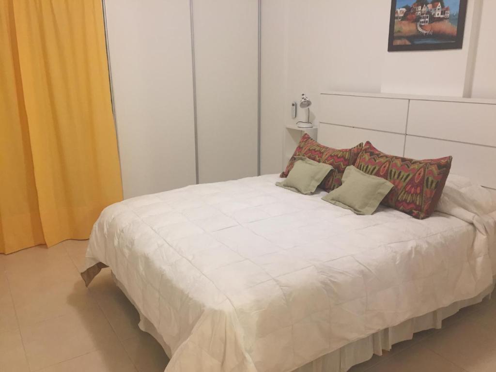 uma cama branca com duas almofadas em cima em Zelarrayan 456 con cochera propia em Bahía Blanca