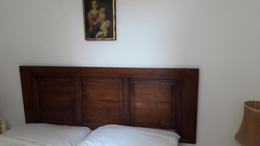 a bedroom with a wooden headboard and a picture on the wall at Appartamento sul Tramonto in Chiessi