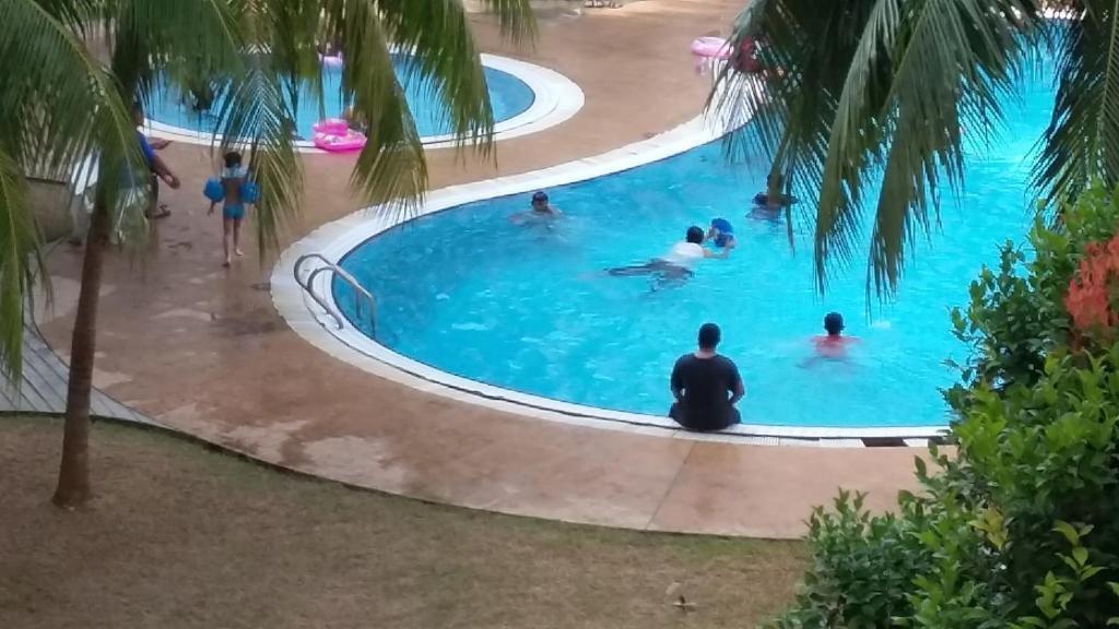 un grupo de personas en la piscina de un complejo en Rose Condo@ Cocobay Beach Resort, en Port Dickson