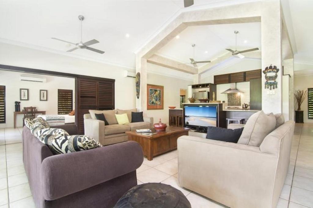 sala de estar con 2 sofás y TV en Tranquility By The Course Port Douglas, en Port Douglas