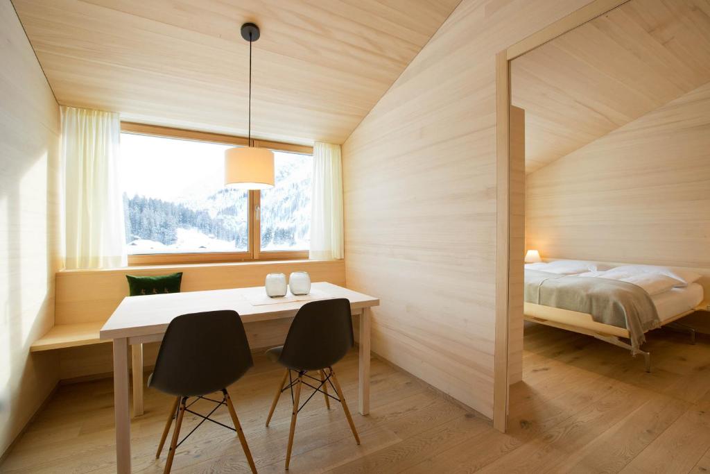 1 dormitorio con 1 cama, mesa y sillas en WarthsAp Apartmenthaus, en Warth am Arlberg