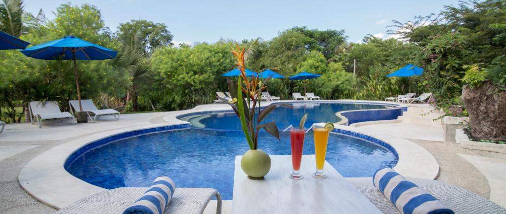 una piscina con sillas y sombrillas junto a una mesa con bebidas en Puri Sari Beach Hotel, en Labuan Bajo