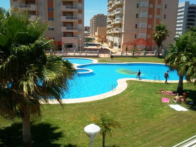 una gran piscina en un parque con palmeras en La Manga, PUERTOMAR, en La Manga del Mar Menor