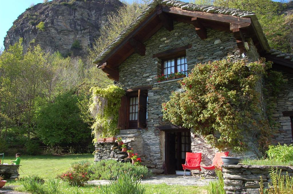 a stone house with red chairs in front of it at Chalet La Baita in Baceno