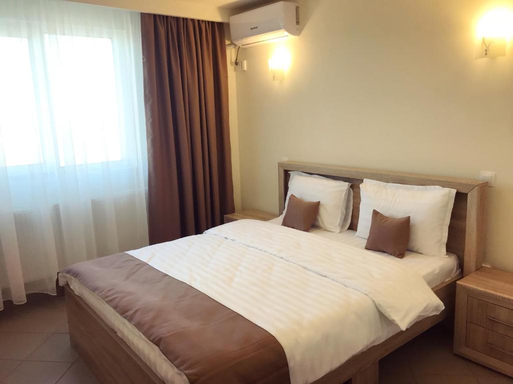 a bedroom with a large bed with white sheets and a window at Casa Bucurr in Afumaţi