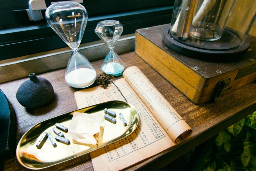 a wooden table with clocks and glasses and a book at H&amp; Jiufen Ore Inn in Jiufen