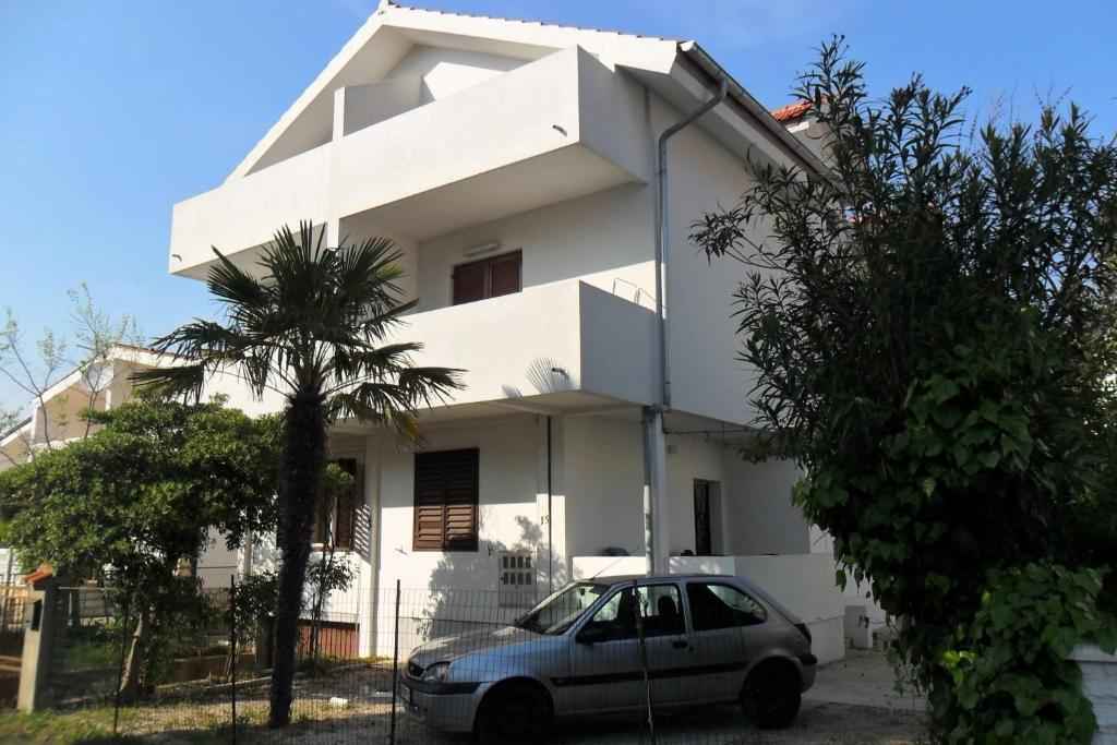 una casa blanca con un coche aparcado delante de ella en Ivago Apartments, en Privlaka