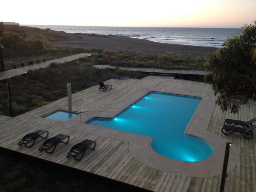 a swimming pool with chairs and the beach at Hotel Punta Sirena in Curanipe