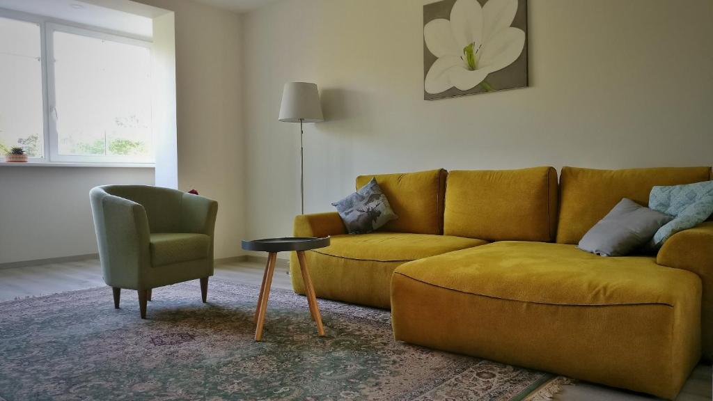 a living room with a yellow couch and a chair at Cozy apartment in Trakai in Trakai