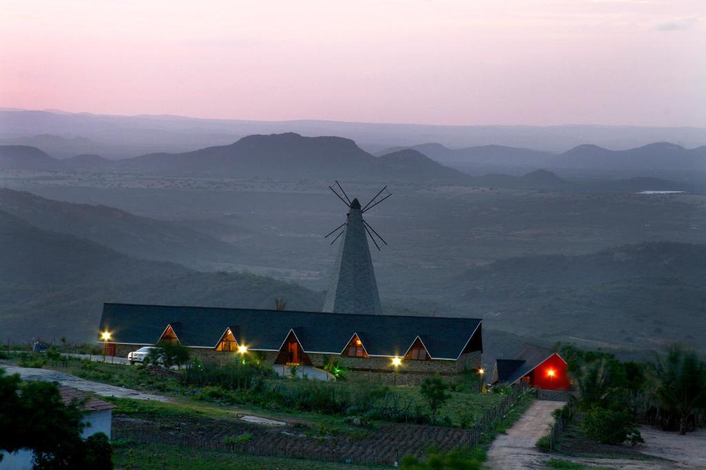 wiatrak na szczycie wzgórza z budynkiem w obiekcie Pousada Pedra Grande w mieście Serra de São Bento