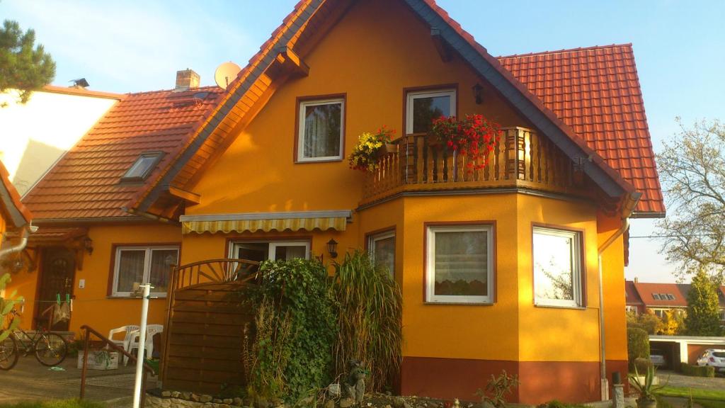 una casa amarilla con un balcón con flores. en Villa Lotti, en Olbersdorf