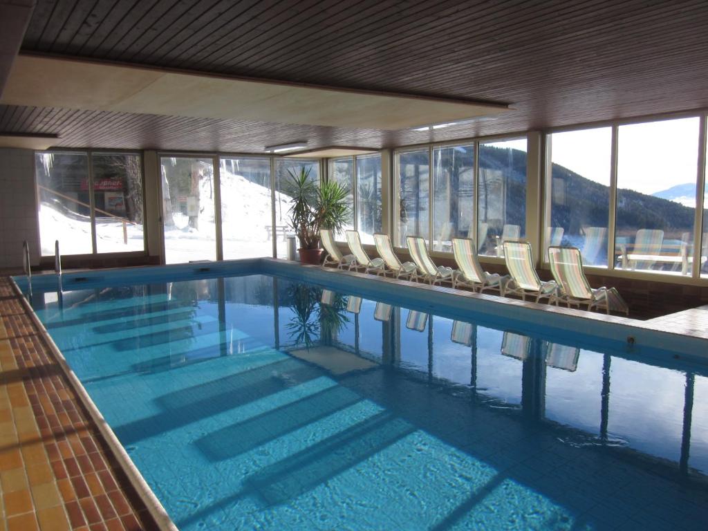 a large swimming pool with chairs and windows at Alpengasthof Waldrast - Koralpe in Sankt Stefan im Lavanttal