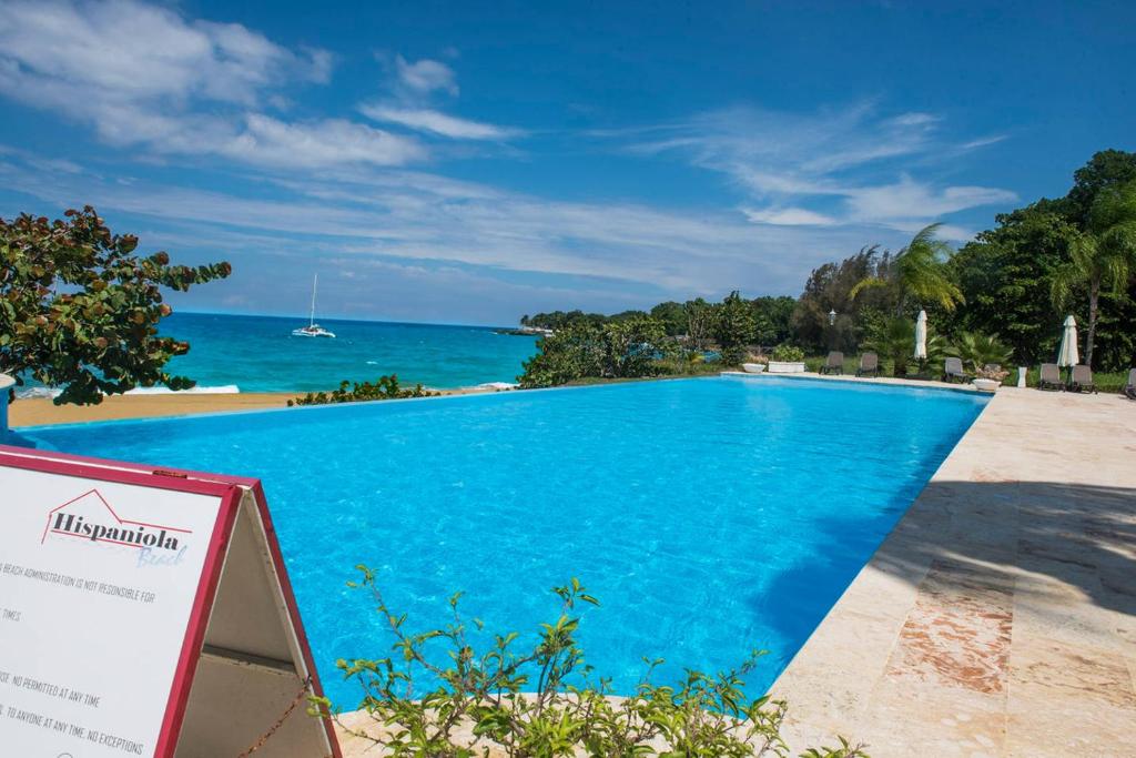 een zwembad van het resort met de oceaan op de achtergrond bij Luxury Oceanview Condo 2 BR/2.5 BA in Sosúa